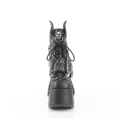 Front view of Demonia Camel‑64 black platform ankle boot with chunky heel, devil horns, claw spikes, barbed wire chain, and metal devil emblem, on a white background.