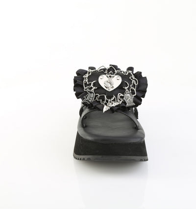 Front view of black Demonia flip-16 platform sandal with silver gothic heart charm, safety pins, and ruffled detailing on the strap.