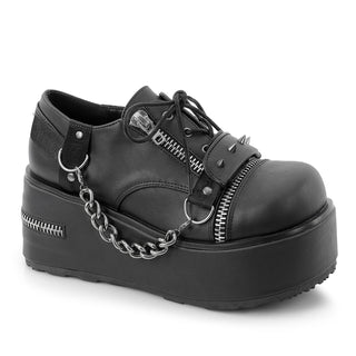 Black Demonia Trashville-24 platform Oxford shoe with a spiked strap, hanging chain and zipper details.