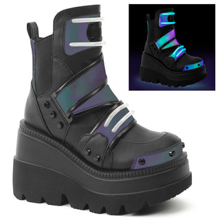 Black wedge platform ankle boots with green reflective panels glowing under UV light, layered straps, and chunky tread sole