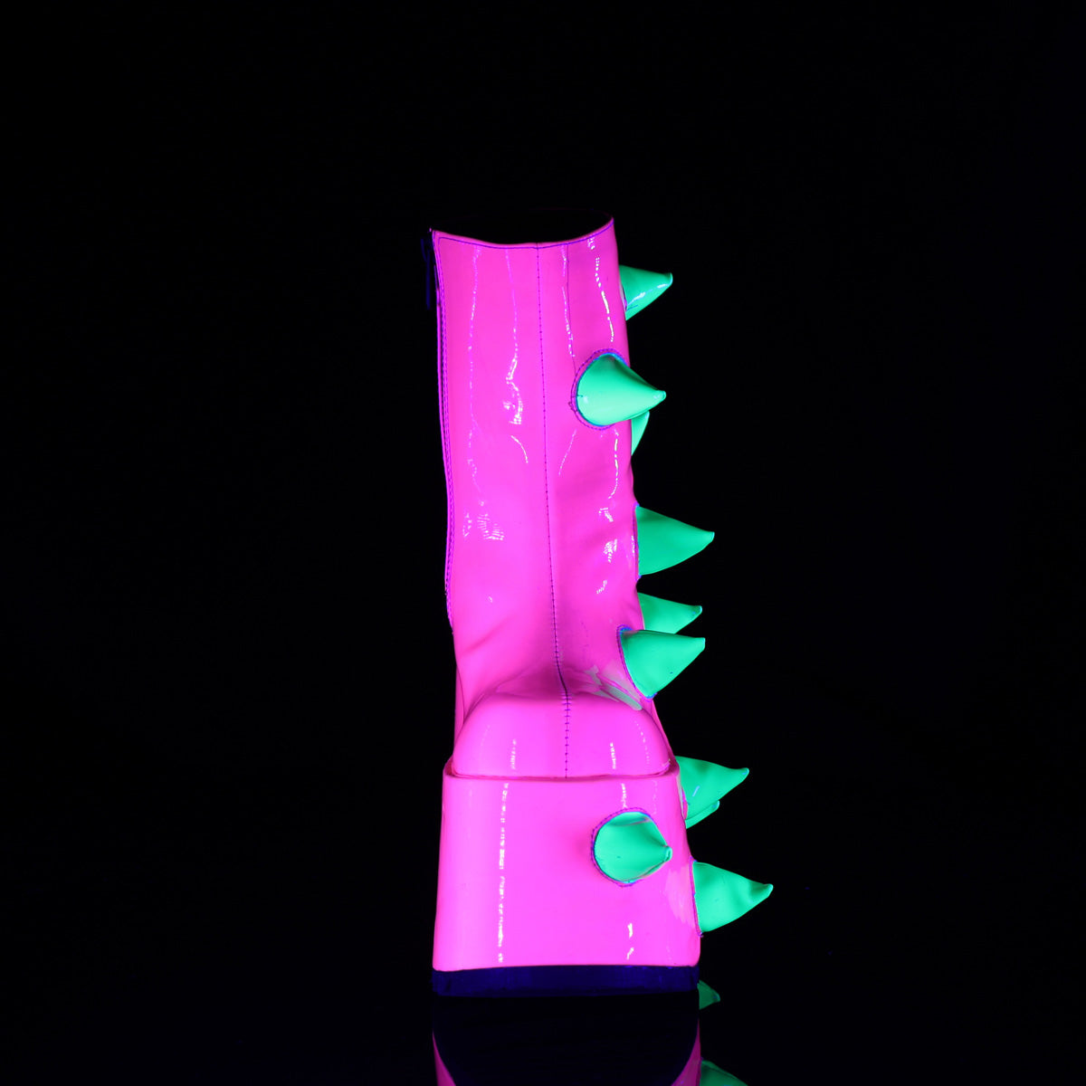 Front view of the Demonia Slay-77 neon pink platform boot with soft green UV-reactive spikes running up the center, photographed under blacklight.