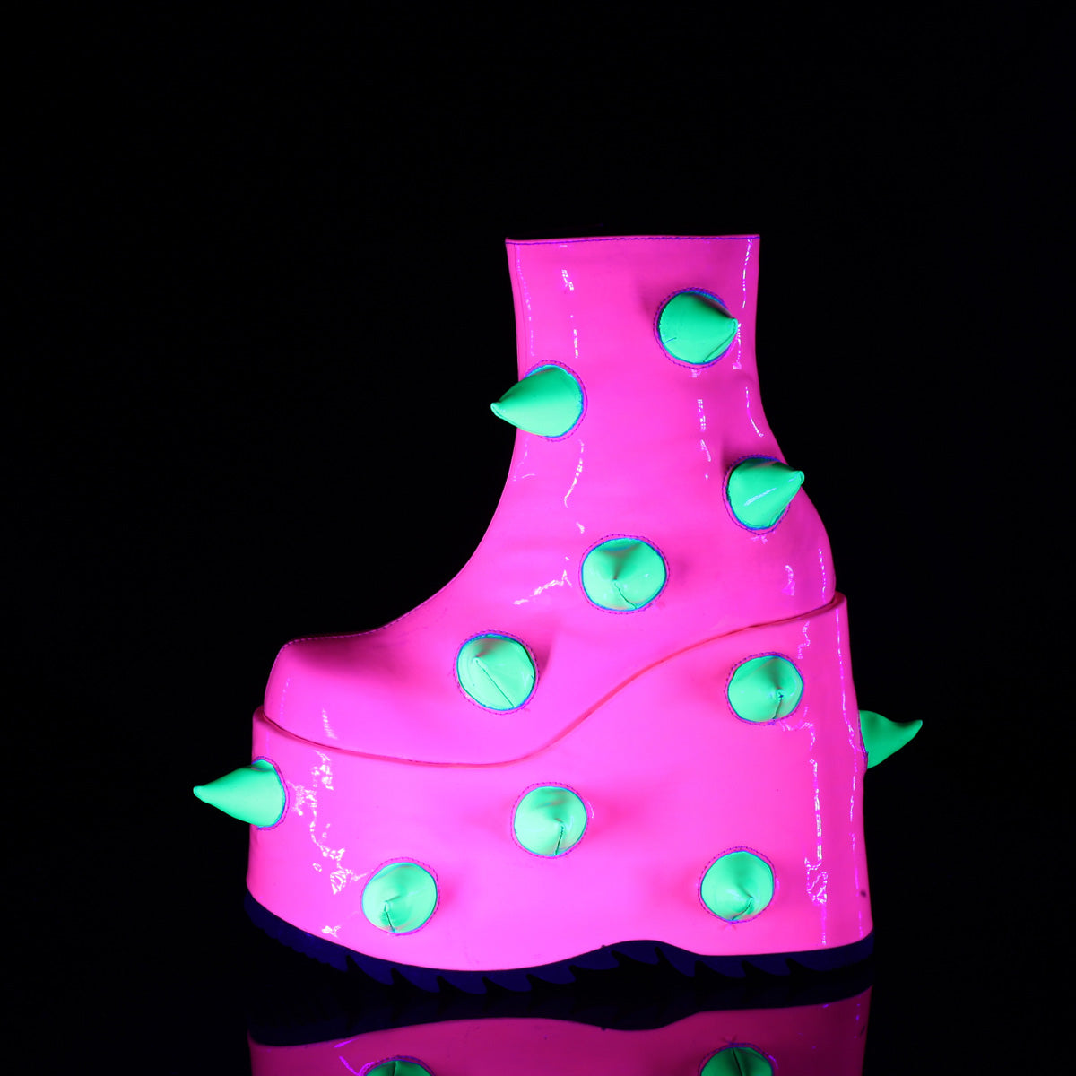 Demonia Slay-77 platform boot in neon pink with soft green spikes, UV-reactive finish, and exaggerated wedge sole, shown under blacklight.