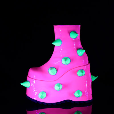 Demonia Slay-77 platform boot in neon pink with soft green spikes, UV-reactive finish, and exaggerated wedge sole, shown under blacklight.