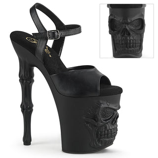 pleaser rapture-809 Matte black 8-inch platform pole sandal with skull‑sculpted base and bone‑style heel, featuring ankle strap, on a white background