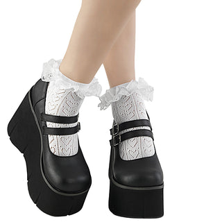 Black platform Mary Jane shoes with double buckle straps, worn with white frilled socks featuring a heart pattern.
