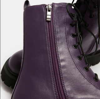 Close-up detail of purple vegan leather combat boots showing the side zipper and lace-up eyelets.